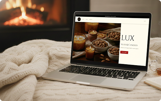 A computer of LUX Nuts & Candles website in a cozy background on a blanket by the fireplace.